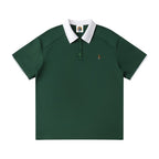 Norman Prince dark green cotton blend short sleeve polo shirt with white collar and sleeve trim, featuring a small embroidered crest.