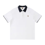 Norman Prince white cotton blend short sleeve polo shirt with navy collar and sleeve trim, featuring a small embroidered logo.
